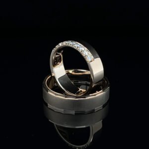 Złote obrączki ślubne Luminous Bond łączą klasyczną formę z nowoczesnym detalem. Jedna zdobiona brylantami, druga o satynowym wykończeniu – razem tworzą symbol harmonii. Tworzone na zamówienie w pracowni jubilerskiej w Katowicach, z możliwością personalizacji.